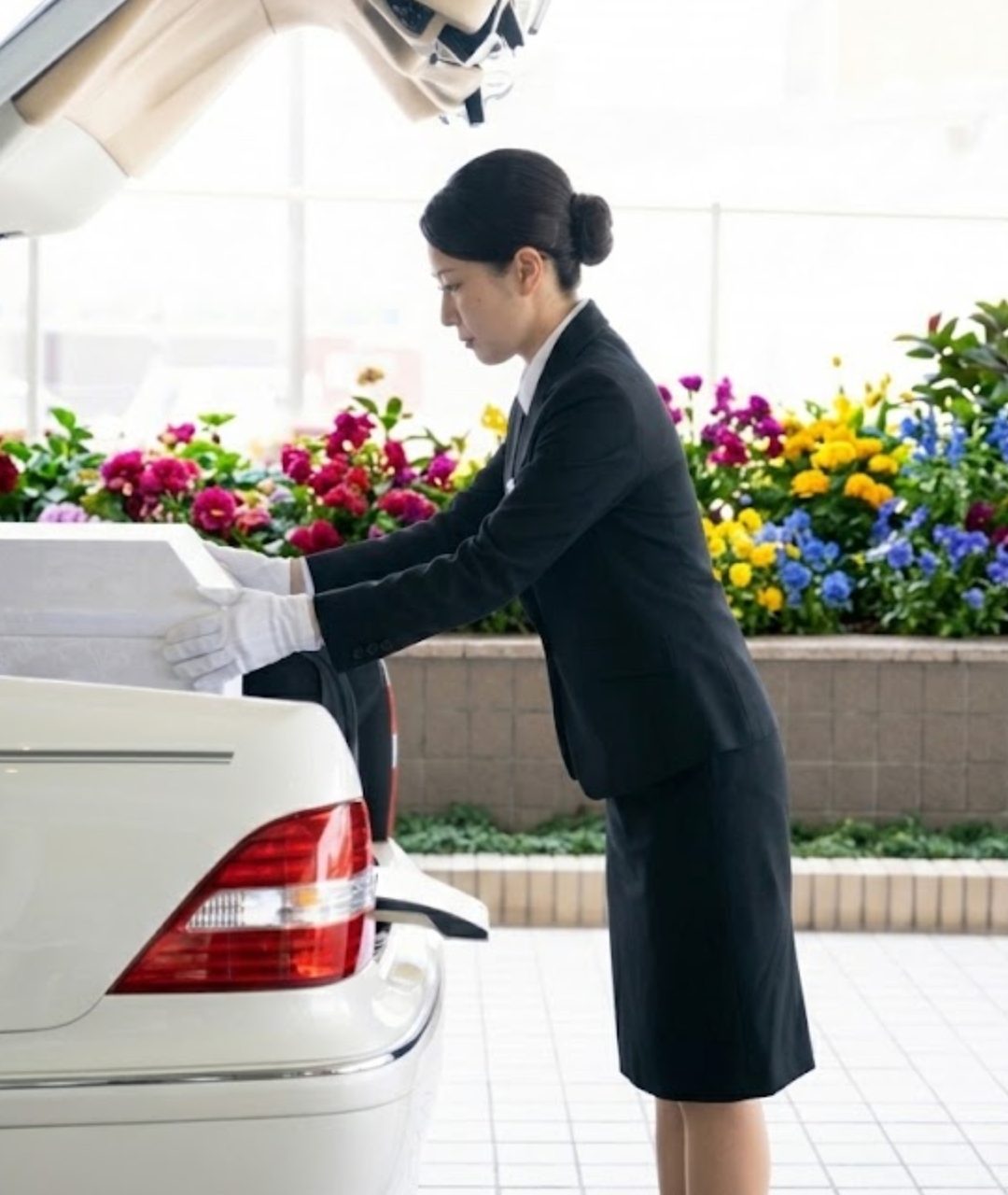 白い手袋で棺を霊柩車へ丁寧に納めるスタッフ